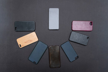 Pile of multicolored plastic back covers for mobile phone on black background. Choice of smart phone protector accessories. A lot of silicone phone backs or skins next to smart phone