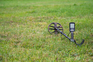 Metal detector laying outdoors on the grass. Close up electronic treasure finder.