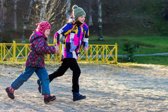 Two little sister girls are actively spending time on a walk, running hand in hand.