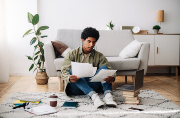 Home education concept. Black teen student making educational project for his online college course indoors