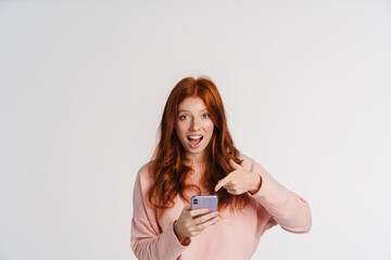 Ginger excited girl holding and pointing finger at cellphone