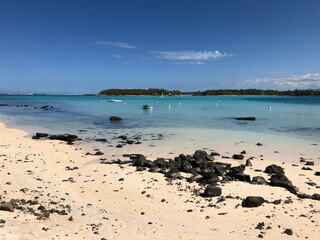 Sand beach and turquoise sea with boats at Blue Bay, Mauritius