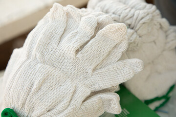 Fototapeta na wymiar Close up and selective focus shot of white fabric glove in new pack bundles shows an equipment for safety and protection in dirty or dangerous works, such as industrial, carpenter and household works