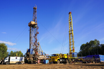 In a row are oil-producing wells. In the background, work is underway to overhaul the well....