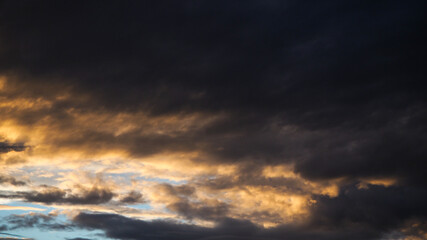 Coucher de soleil et reflets jaunâtres sous un gros nuage à la base bien sombre