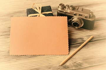 Blank card with old camera and gift box on vintage wooden background