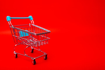 Shopping trolley empty on red wall background, banner, copy space.
