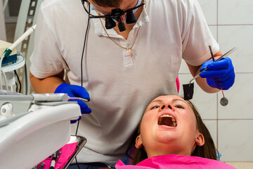 After filling, the dentist removes the excess material from the tooth with a copying tracing paper.