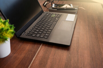 Laptop, smartphone, notebook, and eyeglasses on wooden table