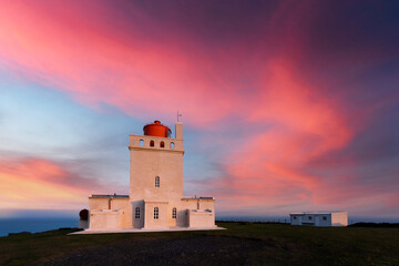 Magic evening view of Dyrholaey Lighthouse at Cape Dyrholaey, south coast of Iceland. Great purple sunset glowing on background. Landscape photography