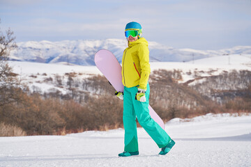 Woman with snowboard against background of mountains