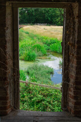 A View From A Derelict Building Out Of A Door Frame Onto A Pand And Grass