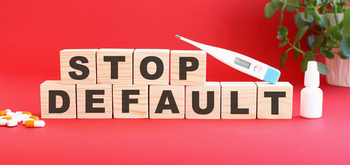 The words STOP DEFAULT is made of wooden cubes on a red background. Medical concept.