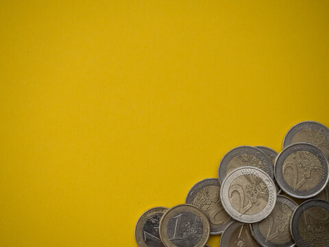 Euro coins in a corner of the picture with yellow background and copy space