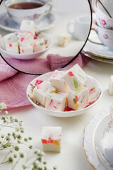 sweet confectionery-Pastila (marshmallows) with candied fruits and black tea in a mug. Tea party in pink style