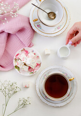 sweet confectionery-Pastila (marshmallows) with candied fruits and black tea in a mug. Tea party in pink style