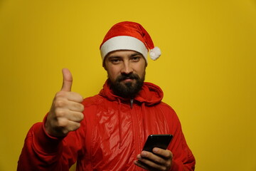 Portrait of a modern Santa Claus with a phone in his hands. Isolated on a yellow background.