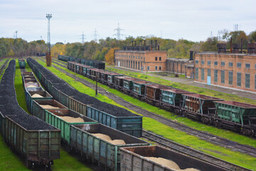 Large metal wagons, railroad runs with small green grass located on the loading production hub. A bright and colorful railway freight station located in the Rechport area of the city of Kamenskoye.