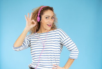 Beautiful woman in headphones listening to music on blue background