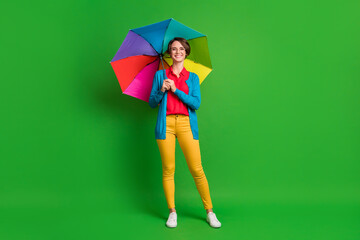 Full length body size photo of girl with bob hair keeping colorful umbrella wearing autumn clothes isolated on bright green color background