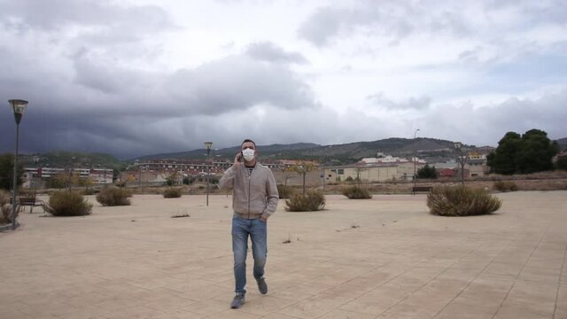 Man wearing reusable face mask using a smartphone in an urban background.