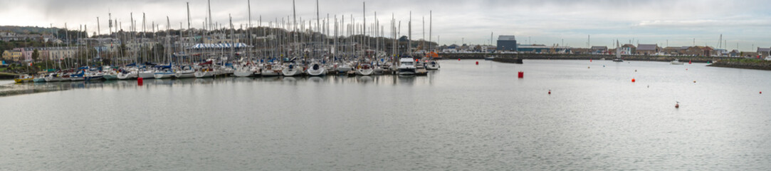 Fototapeta na wymiar Amazing panoramic view at Howth marina bay, near Dublin, Ireland with yachts and boats. Typical small harbour.
