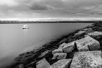 Amazing panoramic view at Howth marina bay, near Dublin, Ireland with boat in the middle. Typical small harbour., stones  in foreground