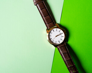 Gold and quartz watch on a green background.