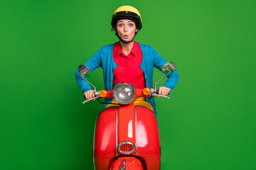 Photo of young beautiful shocked amazed surprised girl wear yellow helmet ride red moped isolated on green color background
