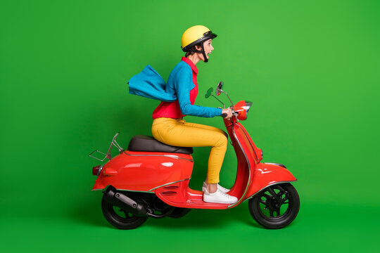 Full size profile side photo of young shocked amazed girl ride fast on red motorcycle isolated on green color background