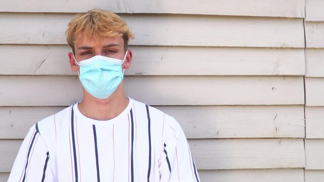 Teenage boy young man wearing face mask outside during Coronavirus COVID-19 Pandemic