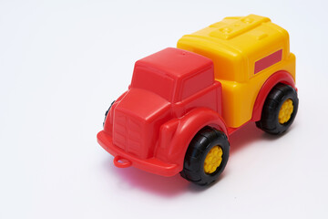 Colorful Children's toy car truck with a red cab and a yellow plastic body on a white background. Flat lay. Copy space.