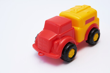 Obraz premium Colorful Children's toy car truck with a red cab and a yellow plastic body on a white background. Flat lay. Copy space.