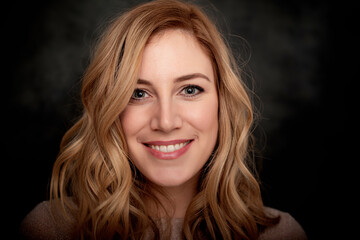 Portrait of a young blonde woman on a dark background.