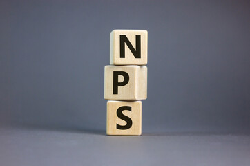 Wood cubes with acronym 'NPS' - 'net promoter score' on a beautiful grey background. Business concept, copy space.