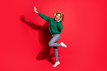 Full size photo of young attractive crazy excited smiling girl listen music in yellow headphones isolated on red color background