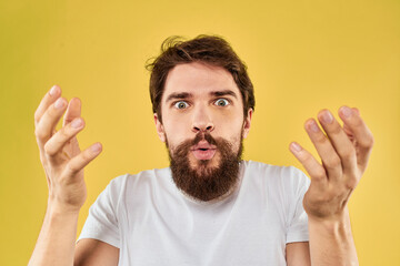 A man in a white t-shirt gestures with his hands lifestyle cropped view yellow background more fun