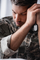Naklejka na ściany i meble sad soldier in camouflage uniform holding military tag