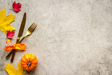 Thanksgiving place setting with cutlery and autumn leaves, top view