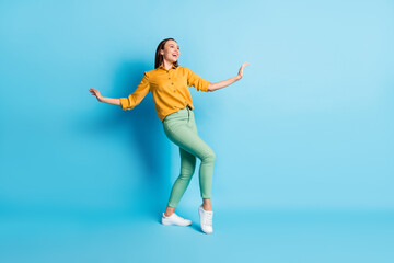 Fototapeta na wymiar Full size photo of cute pretty brunette lady dancing wear shirt trousers sneakers isolated on teal color background