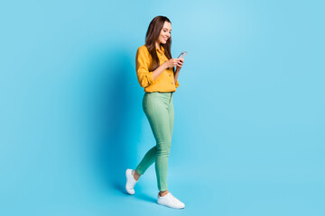 Fototapeta na wymiar Full size profile photo of cute nice brunette lady watch telephone going wear shirt trousers sneakers isolated on teal background