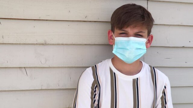 Teenage boy young man wearing face mask outside during Coronavirus COVID-19 Pandemic