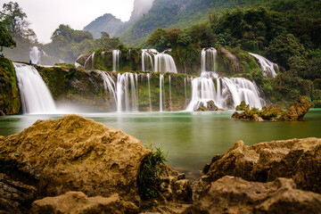 Obraz premium A slow-motion shutter speed capturing the smooth waters of the waterfall at Ban Gioc which straddles the border between China and Vietnam