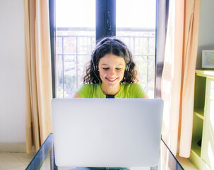 young girl working at home with earphones on video call meeting