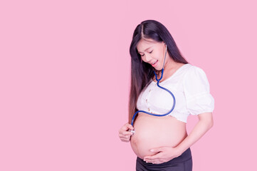 Pregnant Asian women use a stethoscope to touch their belly to hear their unborn baby