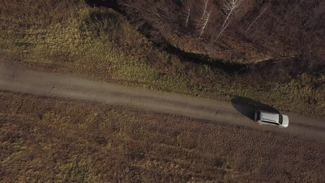 Aerial shot of jeep car riding through the forest off-road. A gray SUV moves from one side to the other on a gravel road. Top view and tracking focus for a moving crossover, 4k
