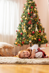 Obraz na płótnie Canvas Little girl lying on the floor by the Christmas tree