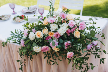 A large bouquet of multi-colored roses lies on the table with a tablecloth. Wedding decorations close-up.