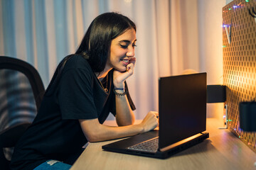 Chica joven morena haciendo vlogs en su cuarto y trabajando en el pc