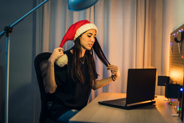 Chica con gorro de papa noel realizando vlog en su cuarto y trabajando en el pc